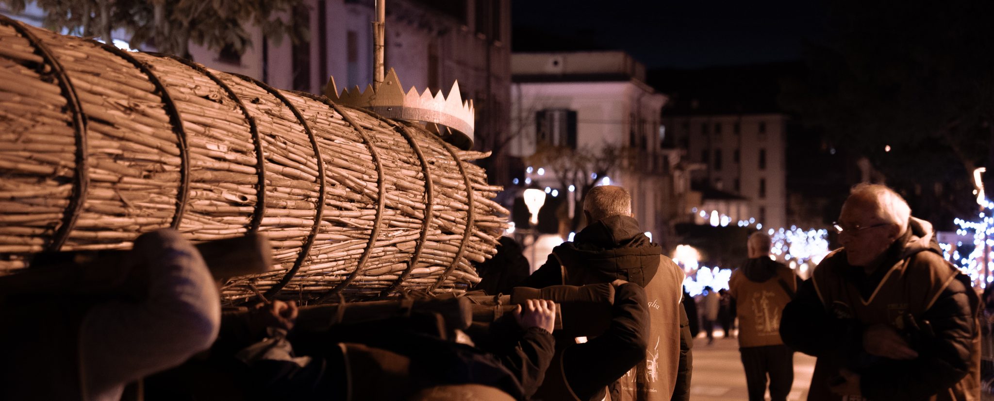 Portatori della Faglia di Oratino con la grande torcia di canne sulle spalle, di notte fra le luci natalizie; foto d'archivio